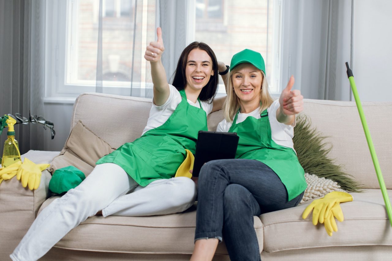 smiling-cleaners-showing-thumbs-up-and-using-tablet